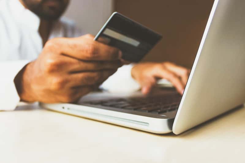 Business owner placing a stock order online with a card in hand